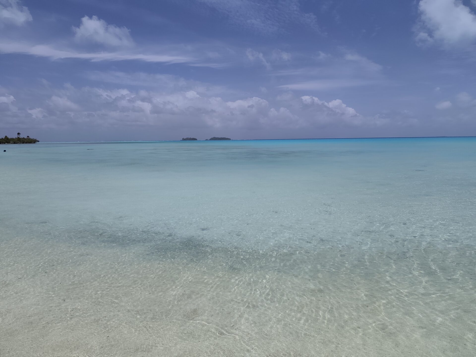 Tropisches türkisfarbenes Lagunenwasser direkt am weißen Sandstrand der Cookinseln, ideal zum Schnorcheln mit Korallenriffen, bunten Fischen und unkompliziertem Einstieg vom Strand aus.